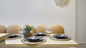 A dining table set with plates, glasses, and a vase with greenery. - Charming Apartment With AC - Le Marais-beaubourg (Paris)