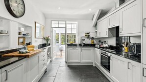 Una cocina moderna con armarios blancos, encimera de madera y un reloj de pared grande.