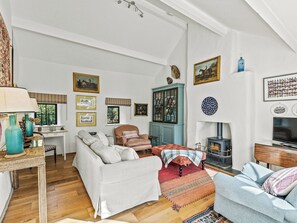 Ein geräumiges Wohnzimmer mit Kamin, bequemen Sitzmöglichkeiten und verschiedenen Dekorationselementen.