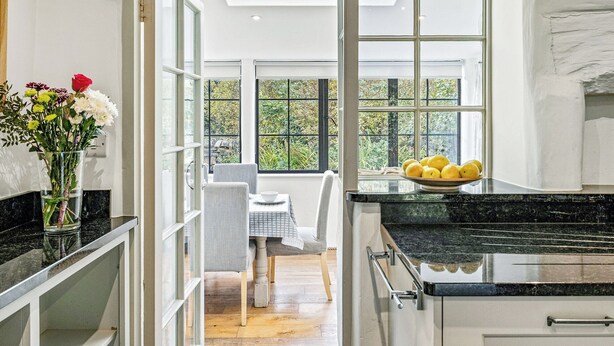 Una cocina moderna con un gran ventanal, un comedor y un florero sobre la encimera.