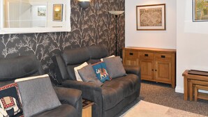 A living room with a black leather sofa, a wooden cabinet, and a framed picture on the wall.
