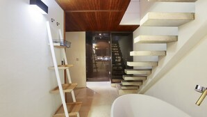 Un interior moderno con una escalera de madera, una bañera blanca y un diseño minimalista.