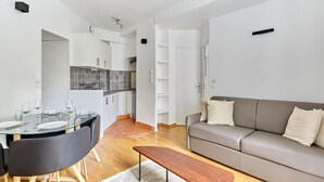 Una sala de estar moderna con una mesa de comedor de cristal, un sofá gris y un banco de madera.