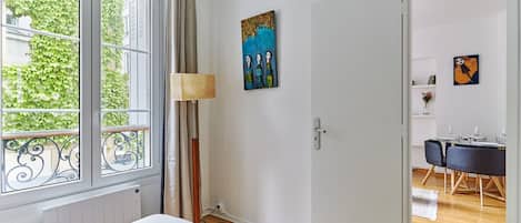 Een slaapkamer met een bed, een lamp en een schilderij aan de muur.