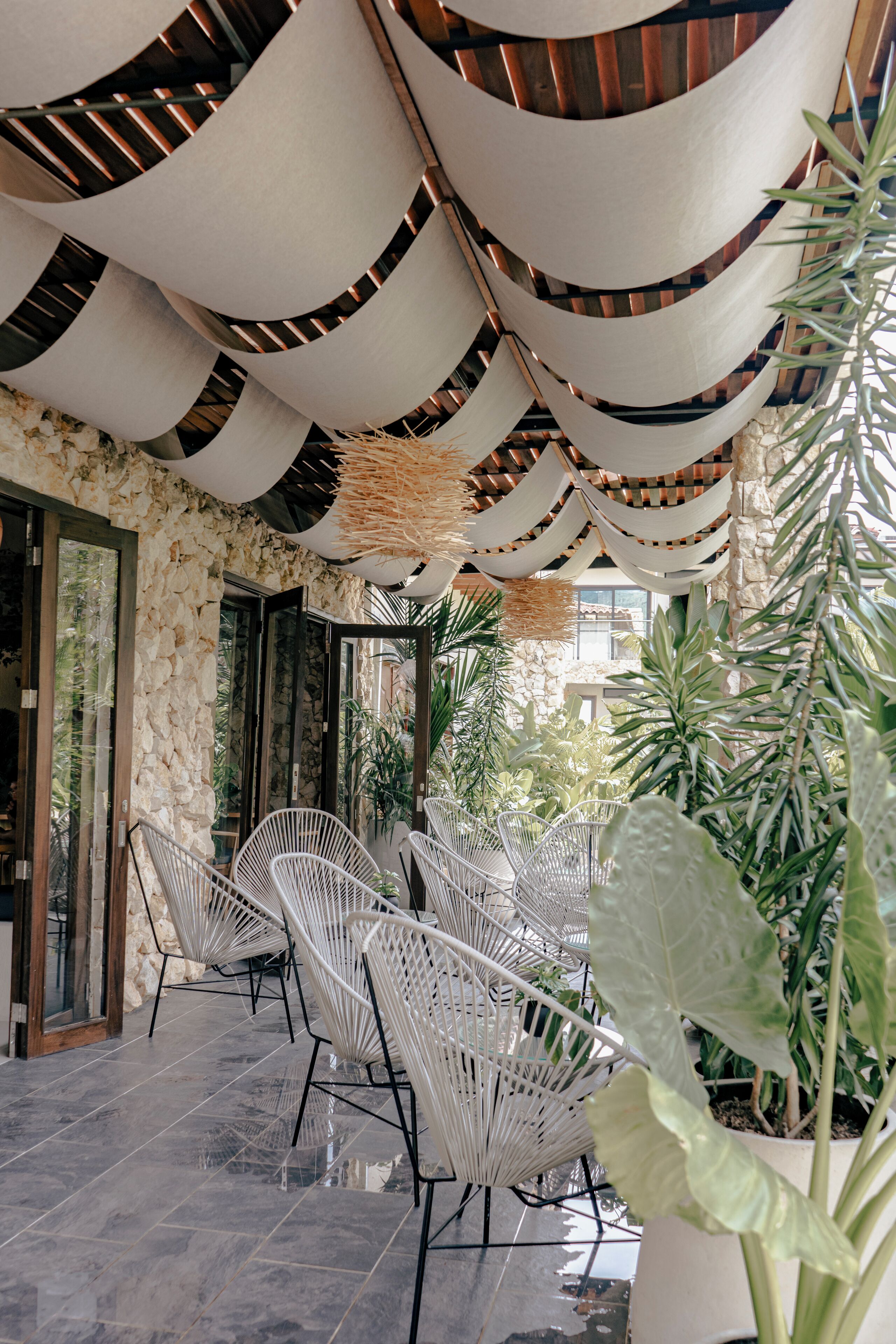 An outdoor seating area with white chairs and a stone wall backdrop.