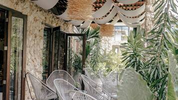 An outdoor seating area with white chairs and a stone wall backdrop.