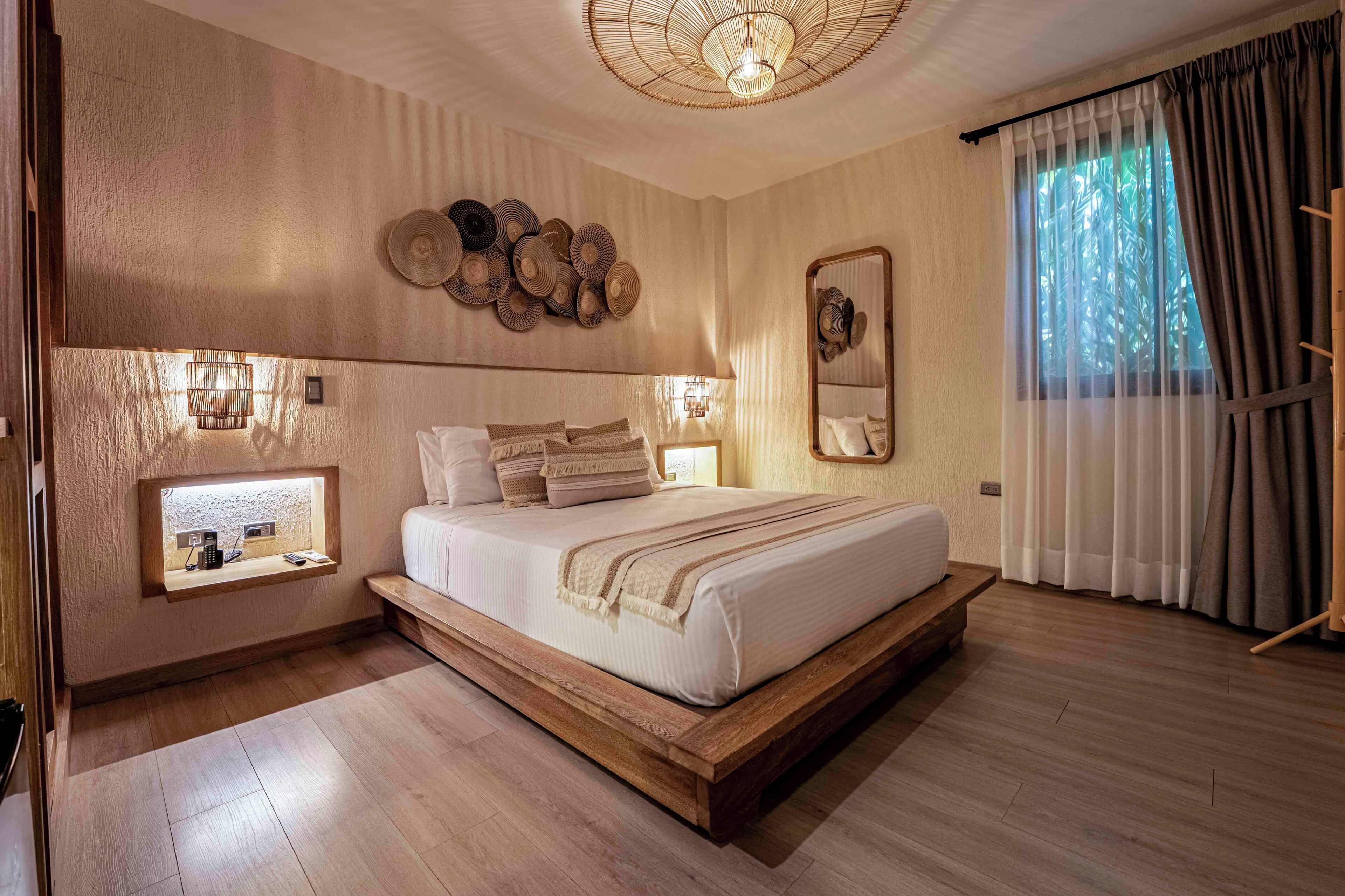 A bedroom with a bed, bedside tables, a wall-mounted light fixture, and a window with curtains.