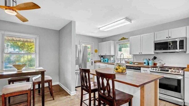 Una cocina moderna con armarios blancos, electrodomésticos de acero inoxidable y una mesa de comedor de madera con sillas.