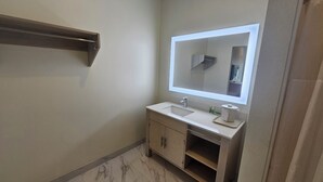 Un bagno con un lavandino bianco, uno specchio e un portasciugamani.