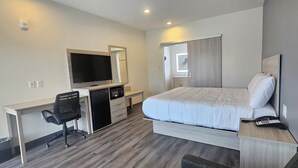Una camera d'albergo con un letto, una scrivania con un computer, una TV e un telefono.