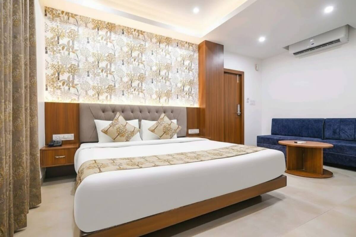 Ein modernes Hotelzimmer mit einem großen Bett, einem blauen Sofa und einer dekorativen Wandverkleidung.