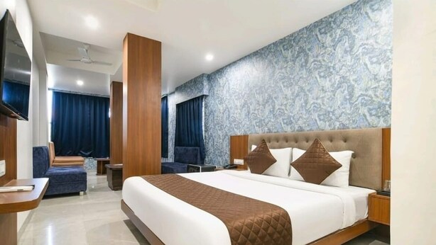 Ein modernes Hotelzimmer mit einem großen Bett, einem Fernseher, einer Sitzecke und einer Wand mit Muster.