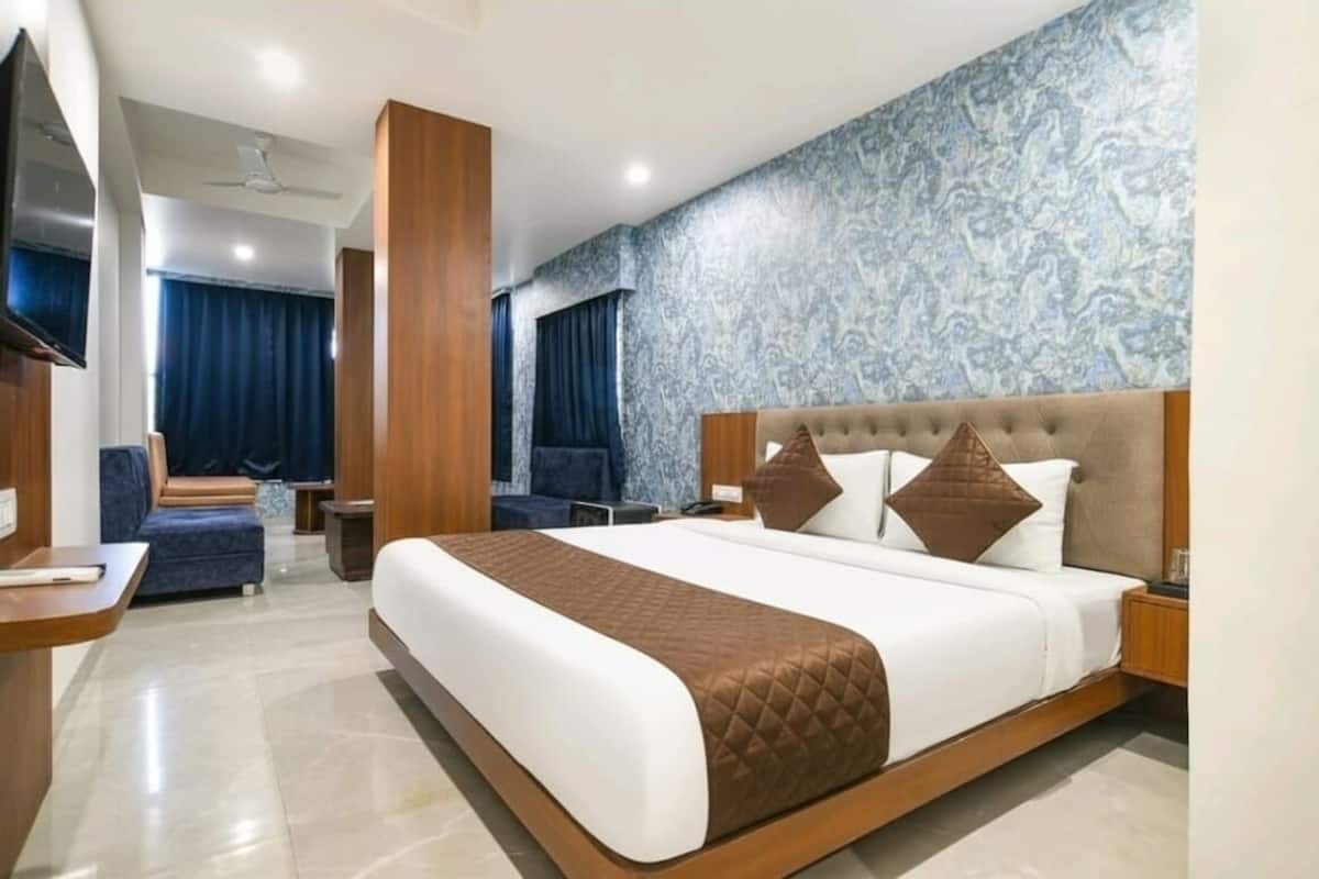 Ein modernes Hotelzimmer mit einem großen Bett, einem Fernseher, einer Sitzecke und einer Wand mit Muster.