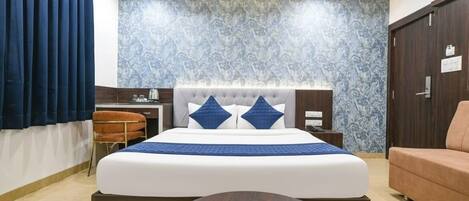 Una habitación de hotel moderna con una cama grande, un escritorio, una silla y un sofá.