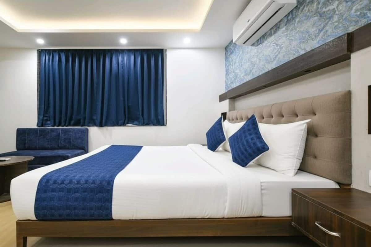 Ein Hotelzimmer mit Bett, Sofa, Nachttisch und Klimaanlage.