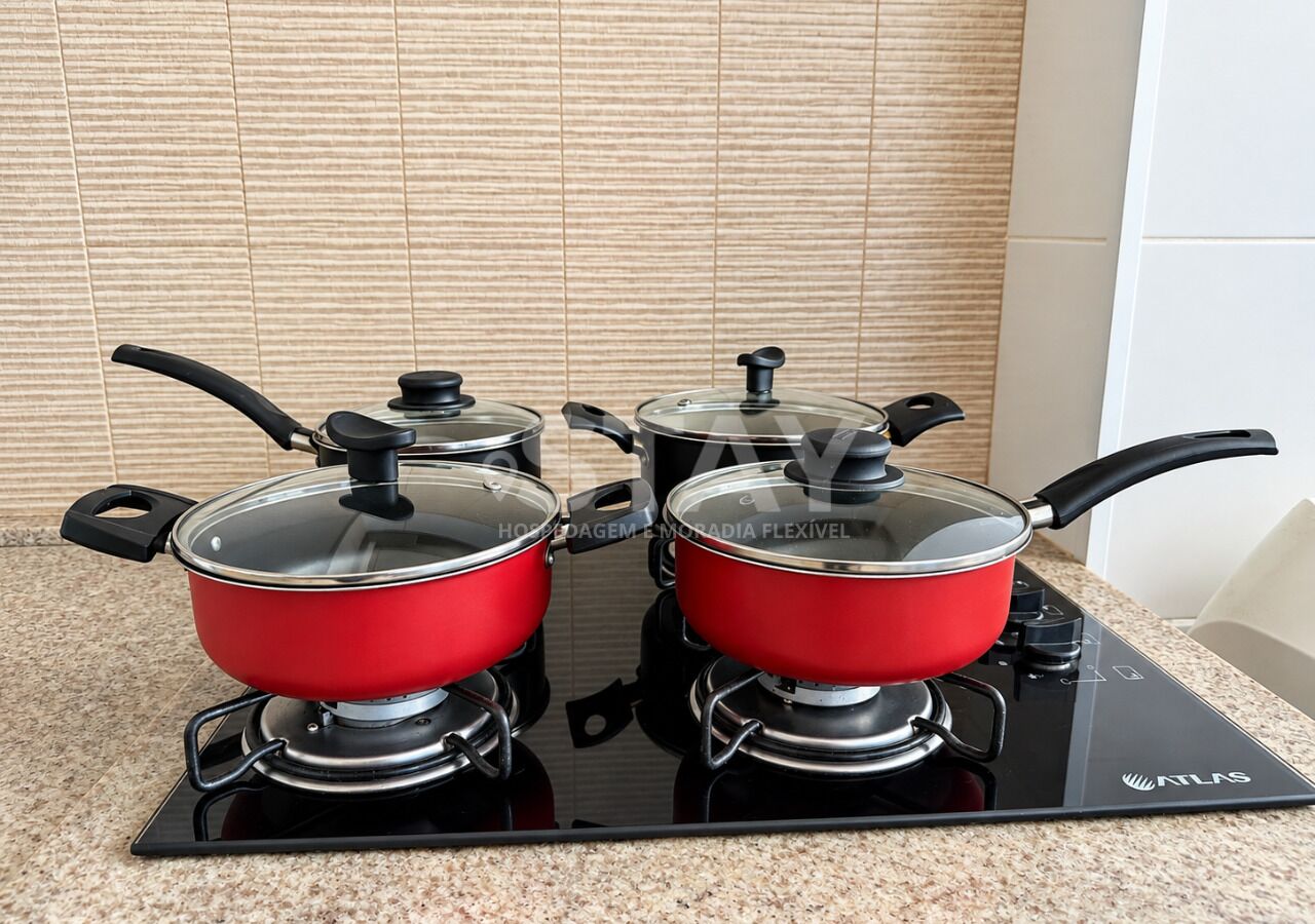 A kitchen with two red pots on a black induction cooktop.