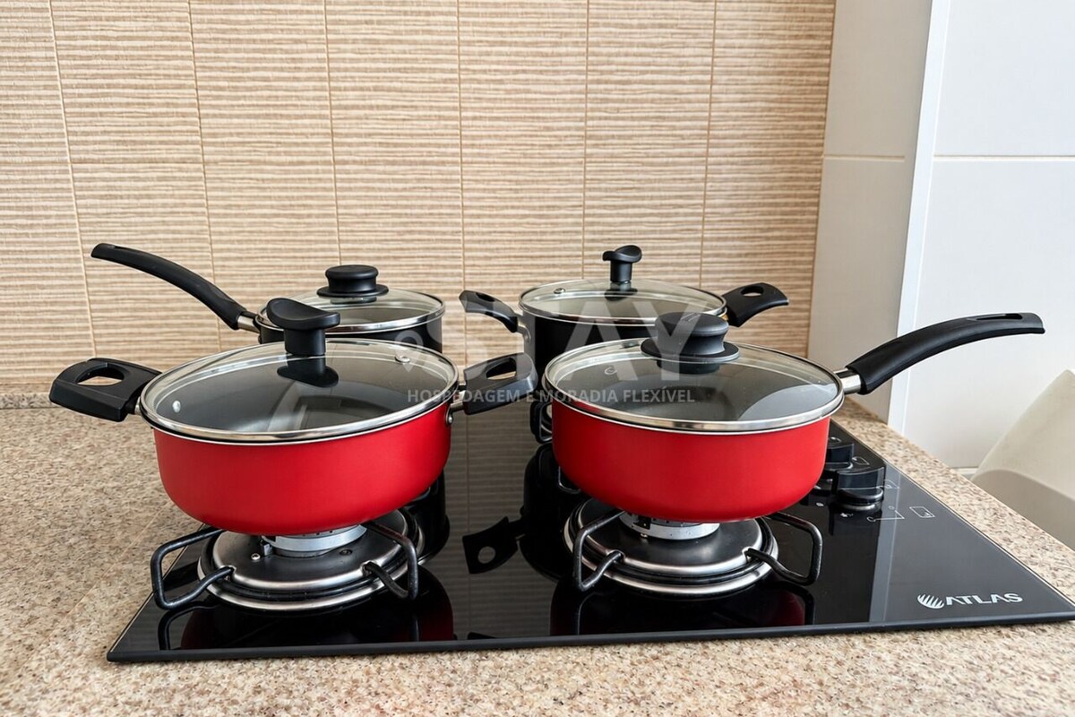 Una cocina con dos ollas rojas sobre una cocina de inducción negra.