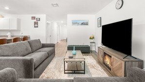 Una sala de estar moderna con un sofá gris, una mesa de centro, un televisor de pantalla plana y una chimenea.