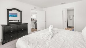 Un dormitorio con una cama grande, un aparador, un espejo y una puerta abierta que da a un baño.