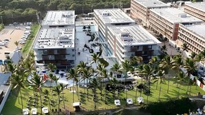An aerial view of a resort with multiple buildings, a beach, and a boat on the water. - Paraíso no Porto Alto Resort (Ipojuca)