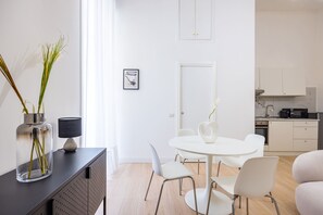 Espaço de estar moderno e minimalista com área de jantar, cozinha e uma grande janela que proporciona luz natural.