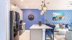 A modern kitchen with a central island, stainless steel appliances, and a blue accent wall.