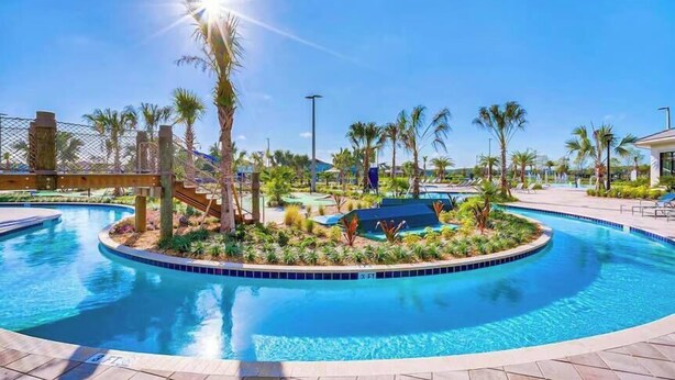 A pool area with palm trees, a covered seating area, and a clear blue sky.