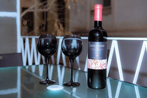 A bottle of OINAH wine and two glasses on a glass table. - Plaka Apartment (Athens)