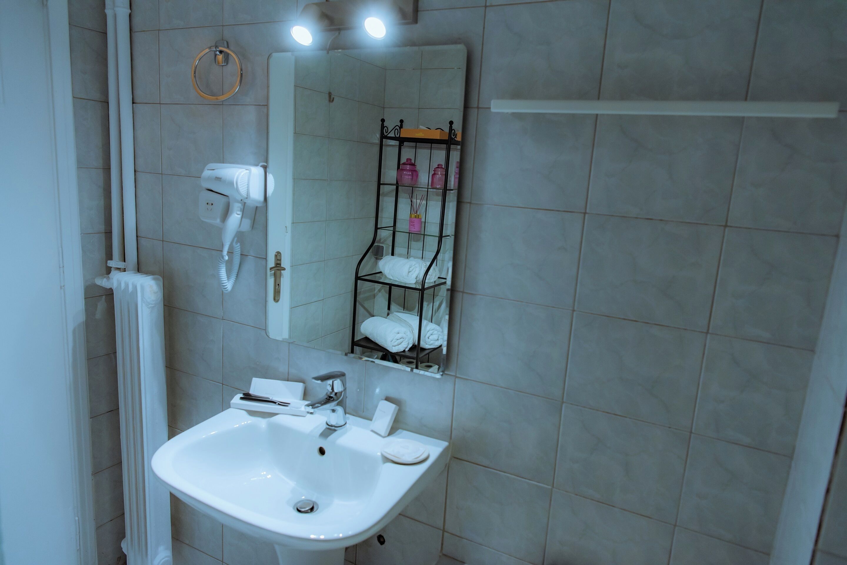 A bathroom with a white sink, a mirror, and a towel rack.