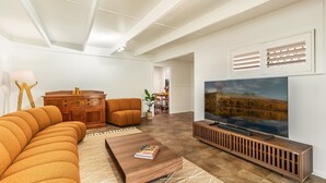 A modern living room with a sofa, coffee table, TV, and a wooden cabinet.