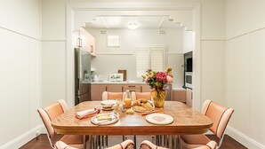A dining area with a wooden table, peach-colored chairs, and a vase with flowers.