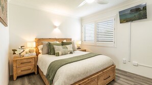 Una camera da letto con un letto con struttura in legno, un comodino con lampada e una finestra con persiane.