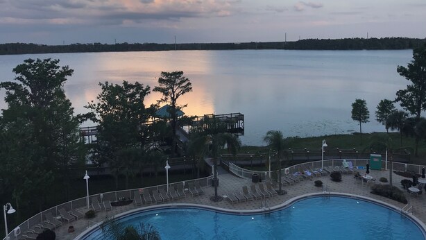 Una piscina con sillas de descanso y un pabellón con vistas a un lago tranquilo.