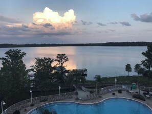 A swimming pool with lounge chairs and a gazebo overlooking a calm lake.