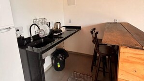 Une cuisine compacte avec un plafond en bois, un plan de travail noir et un petit coin repas comprenant une table et des chaises en bois.