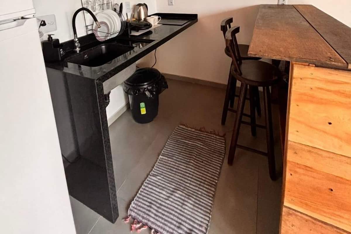 Una cocina compacta con techo de madera, encimera negra y una pequeña zona de comedor con mesa y sillas de madera.