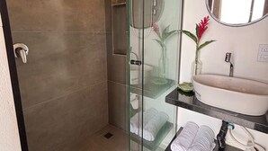 Une salle de bain moderne avec une douche à parois de verre, un lavabo avec un miroir et un porte-serviettes.