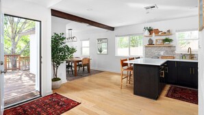 Een moderne keuken met donkere kasten, een groot eiland en een eethoek met houten stoelen.