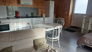 A compact living space with a kitchenette, a dining area, and a bed. - 2-seater studio near Puy du Fou (Bressuire)