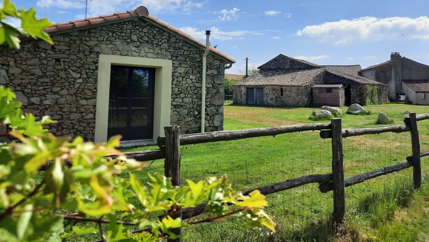 A rustic stone building with a large window and a wooden fence in the foreground. - 2-seater studio near Puy du Fou (Bressuire)