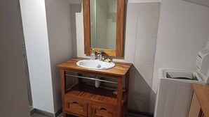 A bathroom with a wooden vanity, a mirror, a sink, and a toilet. - 2-seater studio near Puy du Fou (Bressuire)