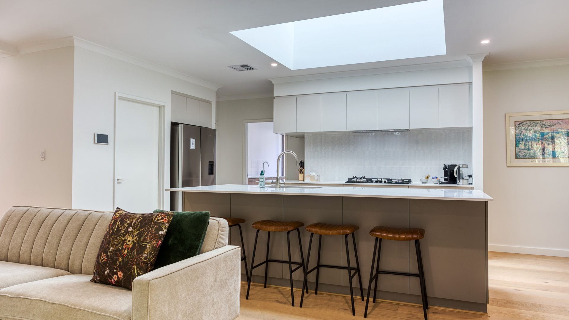 A modern kitchen with a central island, bar stools, and a built-in oven.