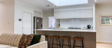 A modern kitchen with a central island, bar stools, and a built-in oven.
