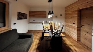 Un soggiorno moderno con zona pranzo, divano e pareti in legno.