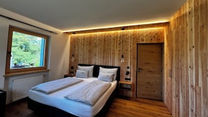 Camera da letto moderna con un letto grande, pareti in legno e una finestra con vista, oltre a una porta.