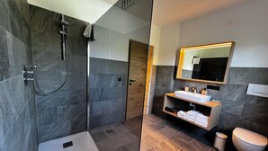 Un bagno moderno con doccia vetrata, un mobile bagno in legno con specchio e il water.