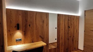 Una stanza con pareti rivestite in legno, una scrivania in legno e una sedia nera.