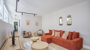 A modern living room with a large sofa, two side tables, and a flat-screen TV. - Sublime and new Apartment Le Marais / Beaubourg (Paris)