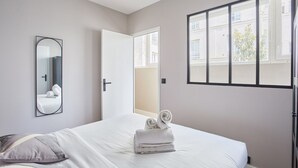 A hotel room with a bed, a mirror, a window, and a door. - Sublime and new Apartment Le Marais / Beaubourg (Paris)
