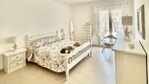 Un dormitorio amplio con una cama grande, un aparador, un escritorio y una silla.